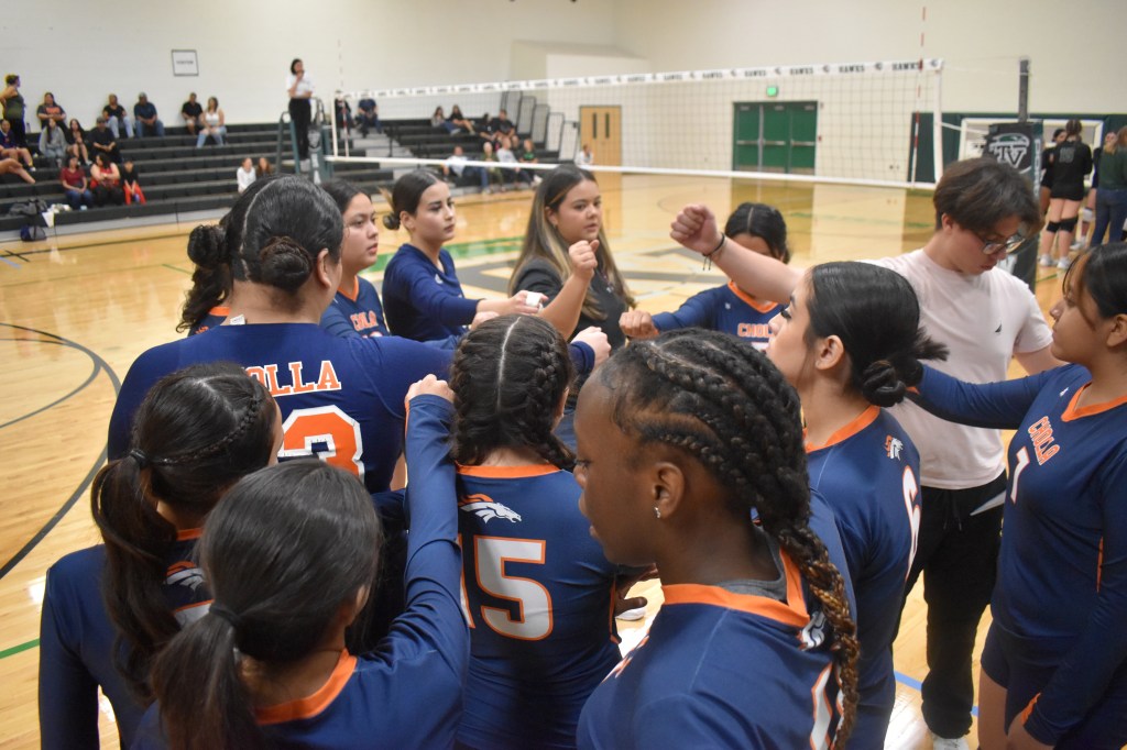 JV team about to make a call with fist together right after 1 set. View from above girl's fists 