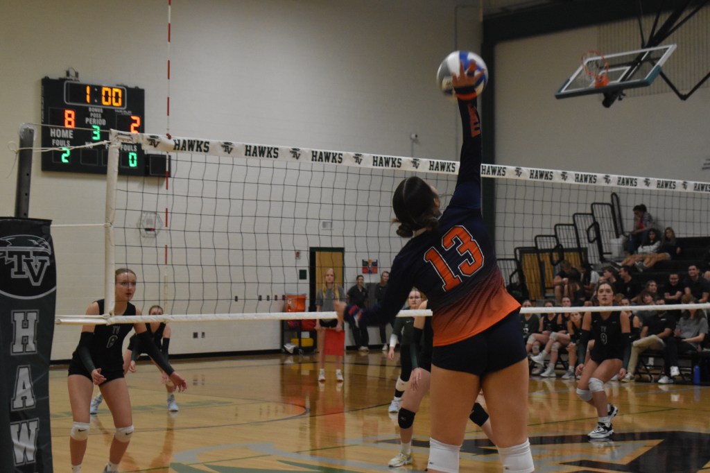 Varsity player Camila making contact with ball about to spike the ball on the opposite side of the court