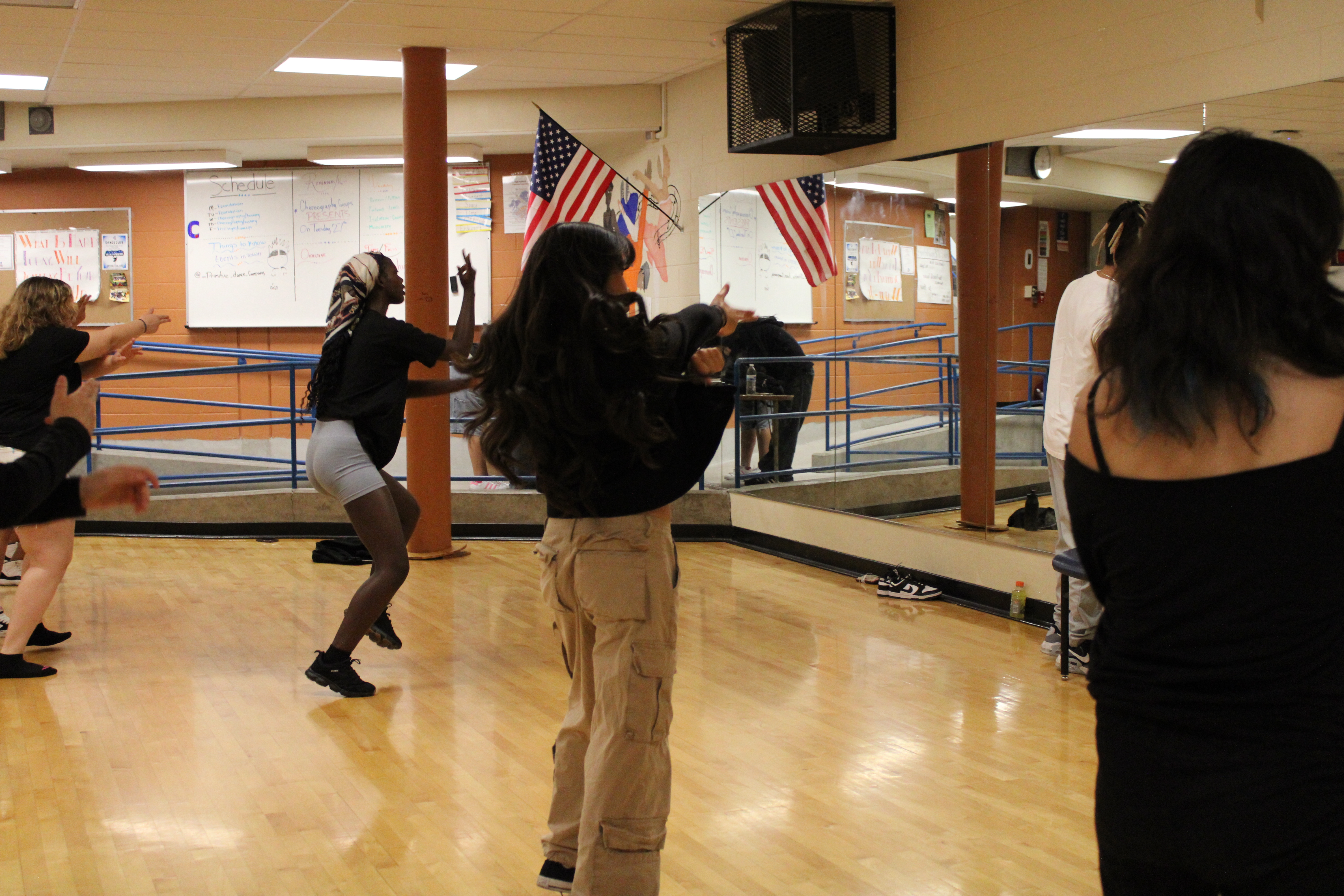 Several dancers practicing energetically in the dance rooms wooden floors