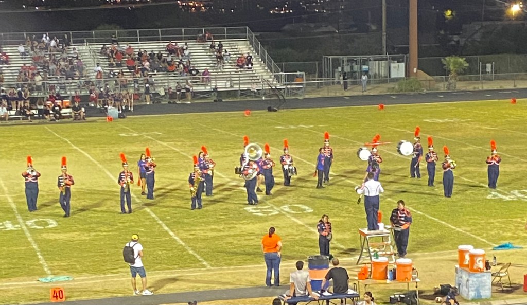 The marching band playing in the field during a game.