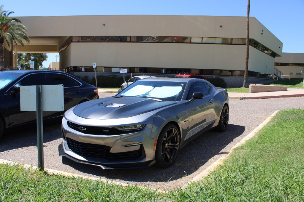 A picture of a grey and black Camero in the faculty parking lot taken in the morning.
