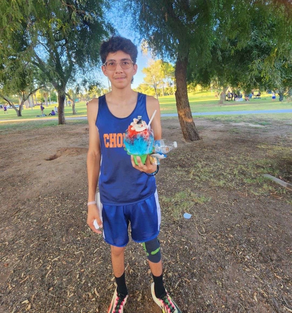 Male standing with a cup of ice cream in his hands, after a cross country meet