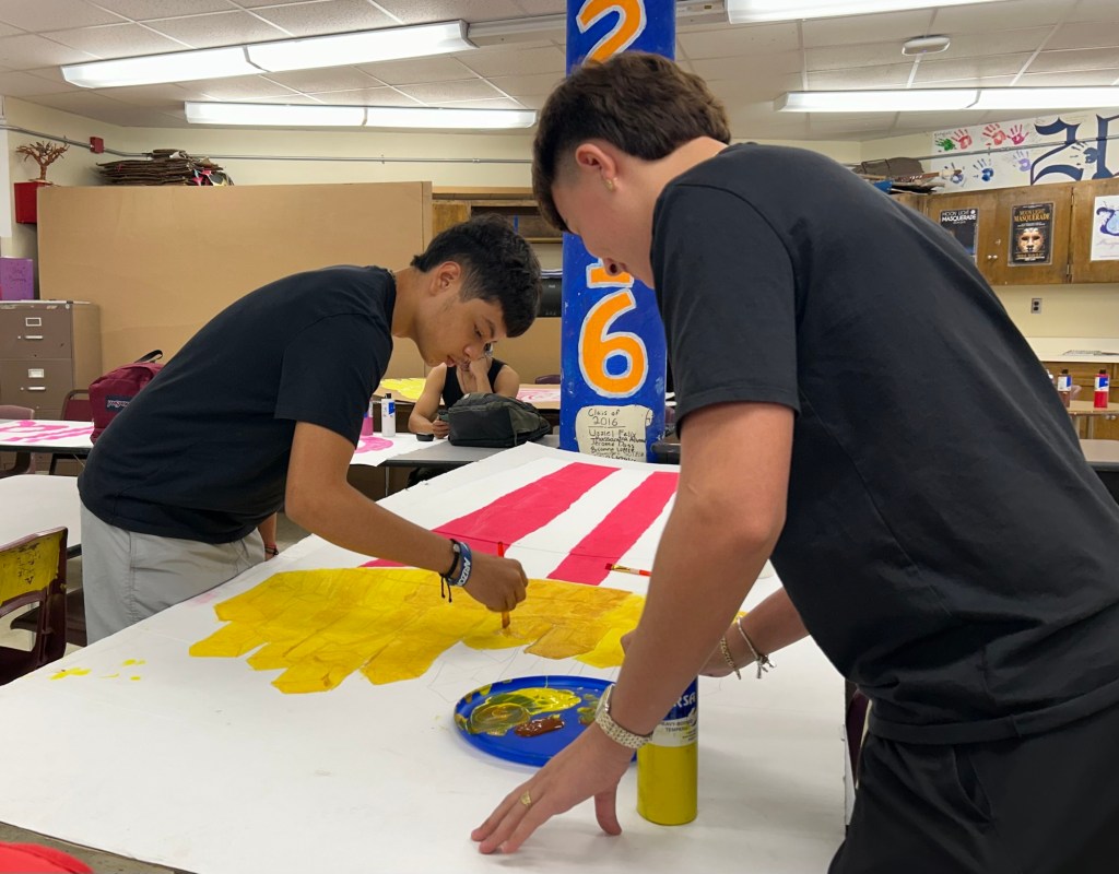 Two teenagers painting a bag of frenchfries