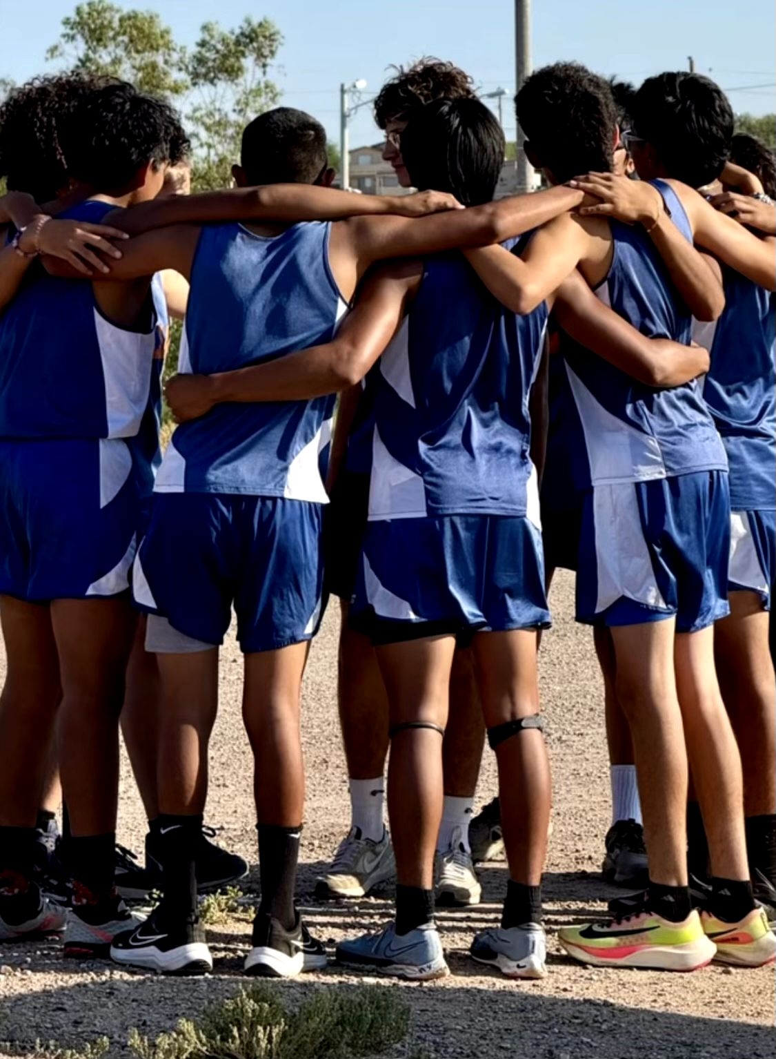 Males athletes, with dark blue cross country uniforms, who are reunite, before the meet
