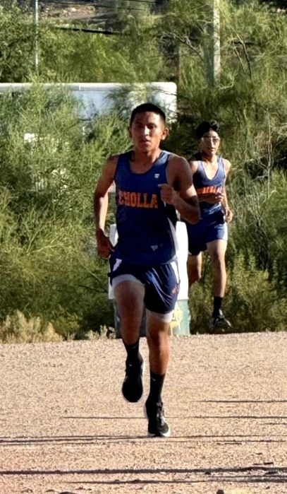 Male running, wearing a dark blue cross country t-shirt.
