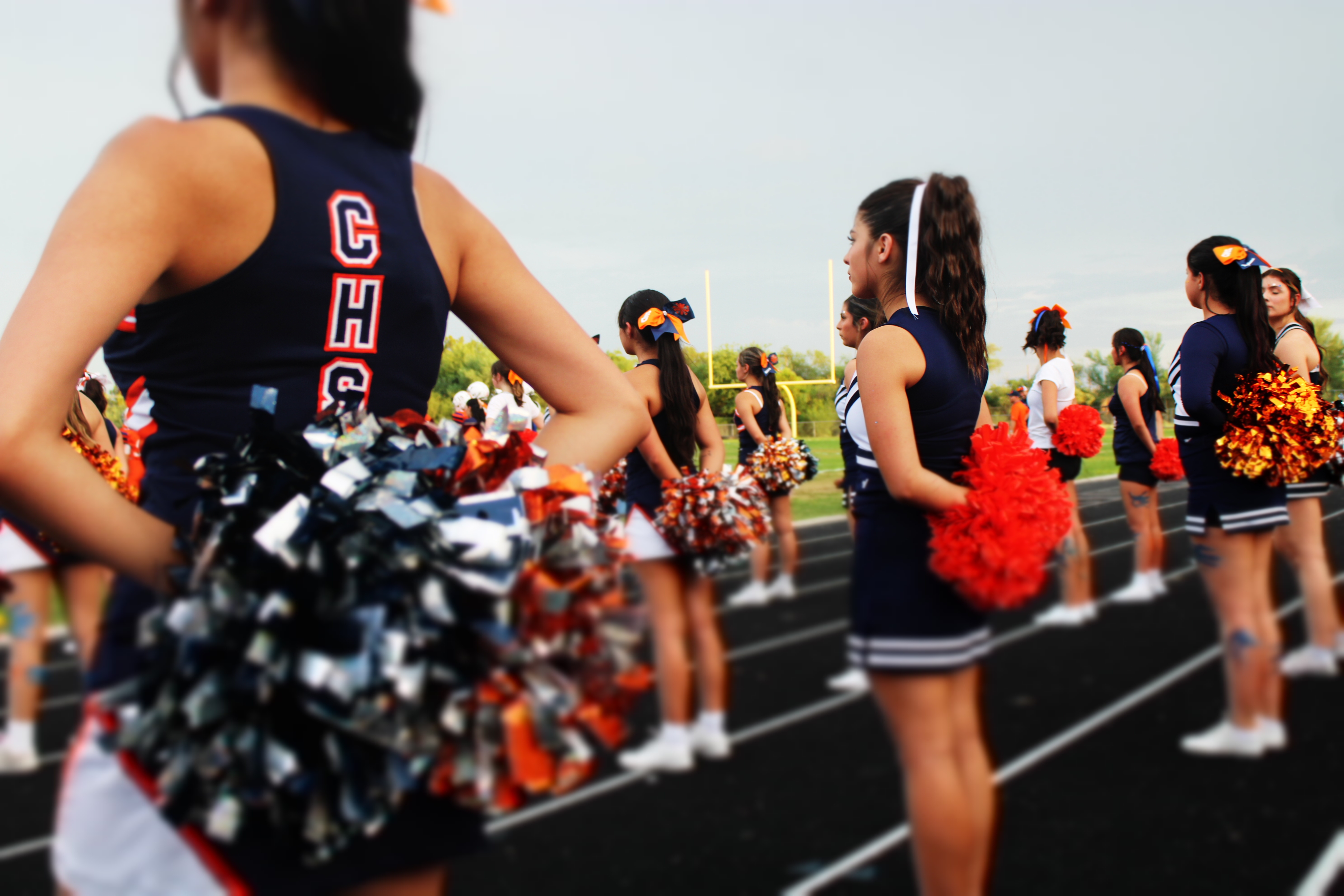 Cheerleaders standing waiting for a cheer to start on the sidelines
