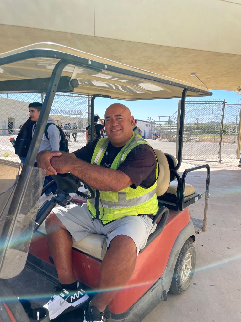 bald chubby Hispanic man smiling on a golf cart 