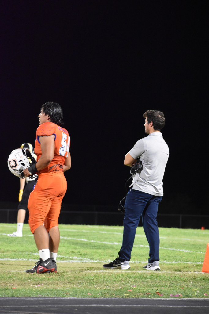 Coach & football player on the sidelines.


